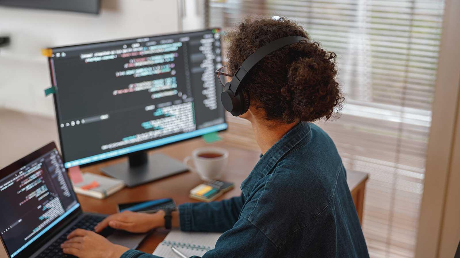 Person sitting at desk with monitors working on coding representing Computer Science program at Clarkson